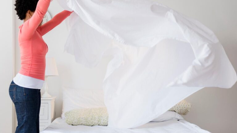 A housewife folding her room's bed sheets beautifully